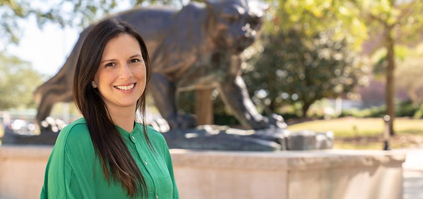 Jennifer Palomo-Gregory in front of jaguar statue on campus.